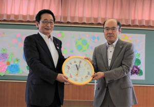 寄贈されたリズム時計を手にするリズム時計(株)荒井部長と畠山市長