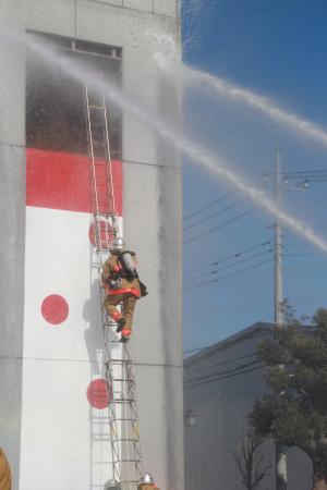 高層階にいる避難者を救出するため梯子を上る消防士