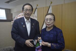 褒章のメダルを持つ大場玲子さんと市長